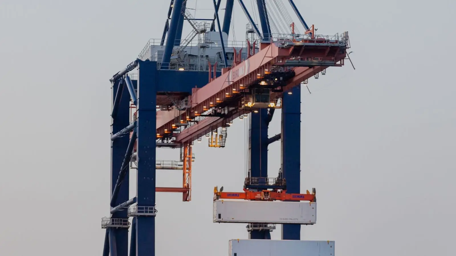 Cargo container terminal at the Port of Rotterdam at twilight, gantry cranes lit against the sky